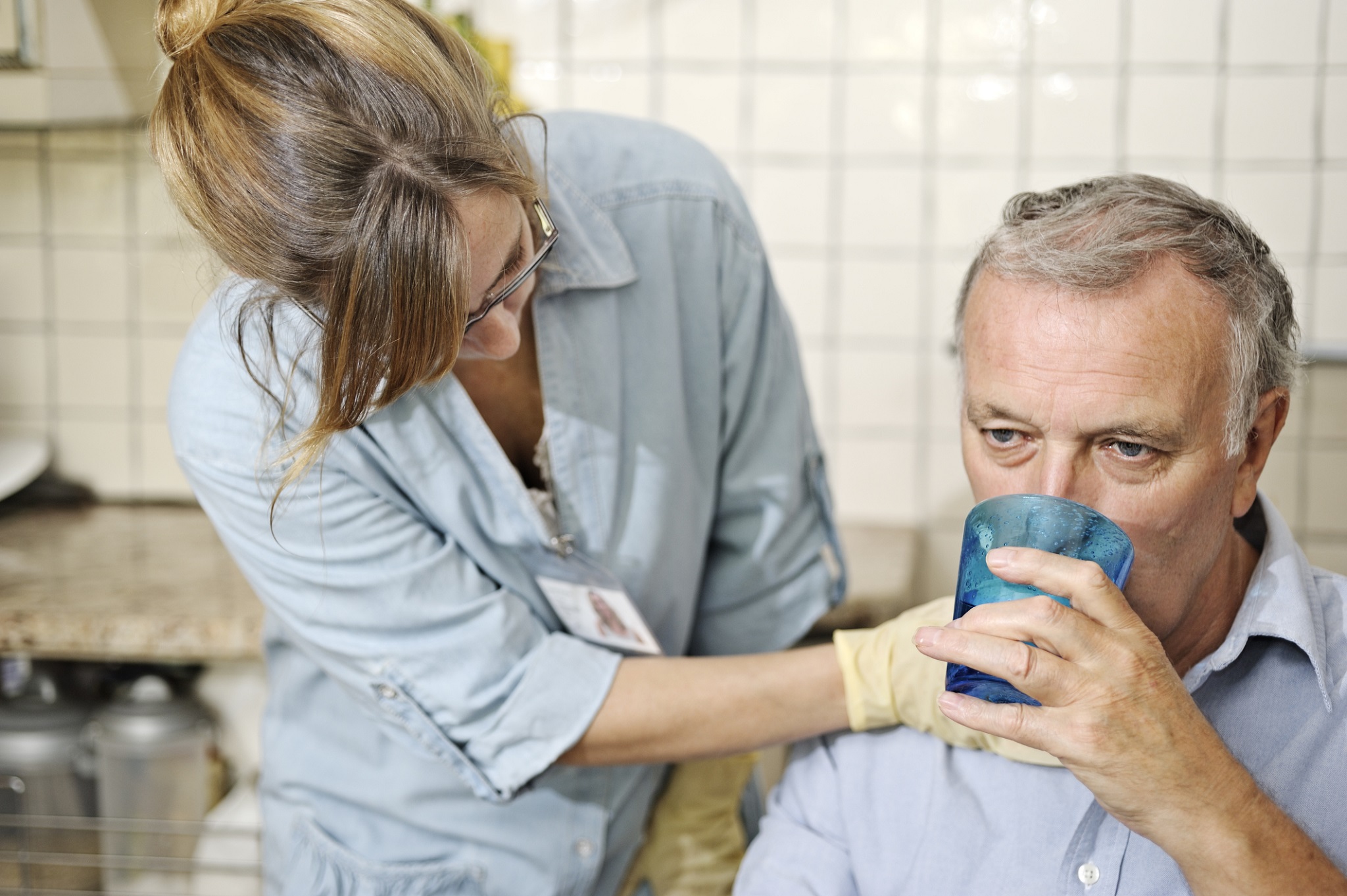 Care home nurse helping a man drink