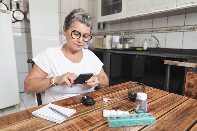 A woman at a table with medication and a notebook